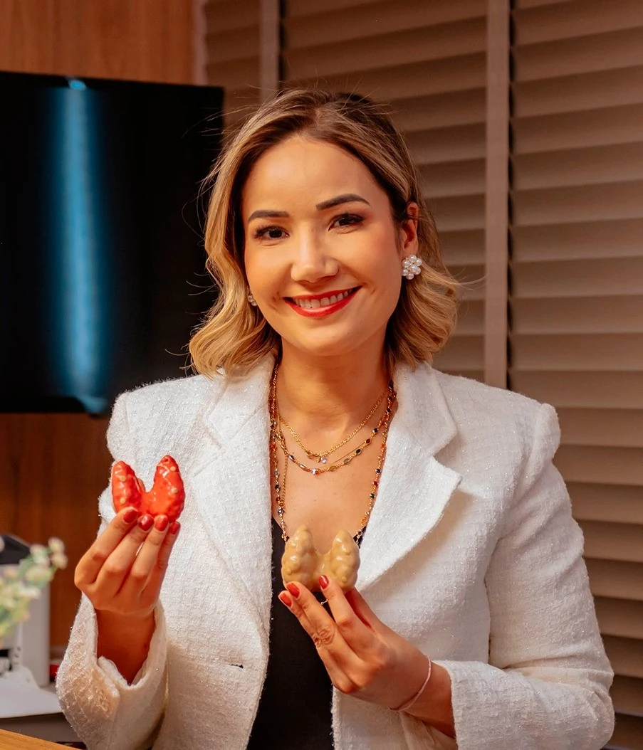 Dra. Paula Mattos segurando modelos anatômicos da tireoide